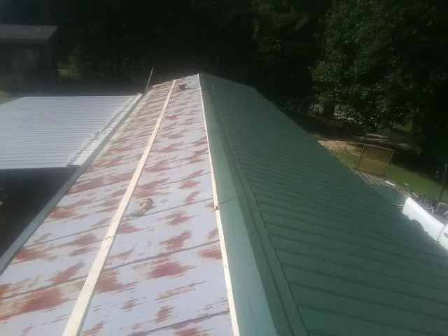 Old rusted panels beside newly installed green metal roofing — Wind Damage Roof Repair by Roofing Brothers in Youngtown