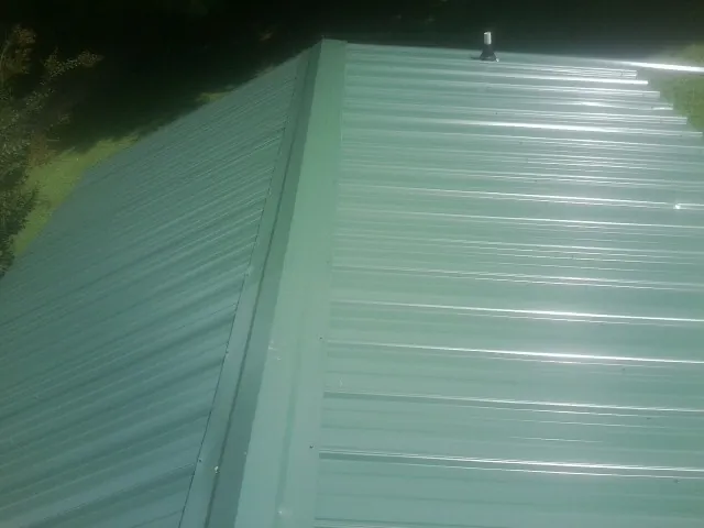 New green metal panels meeting at the ridge of a roof — Flat Roof Repair work by our crew in Youngtown