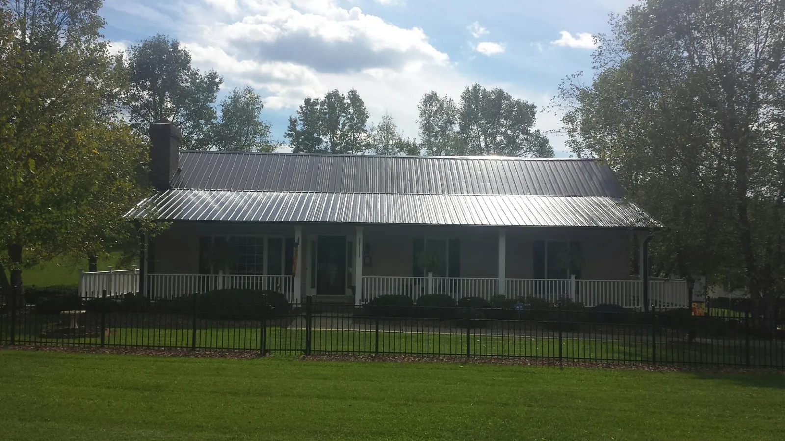 Gray metal roof on a brick ranch with a full width front porch — Gutter Guard Installation work by our crew in Youngtown