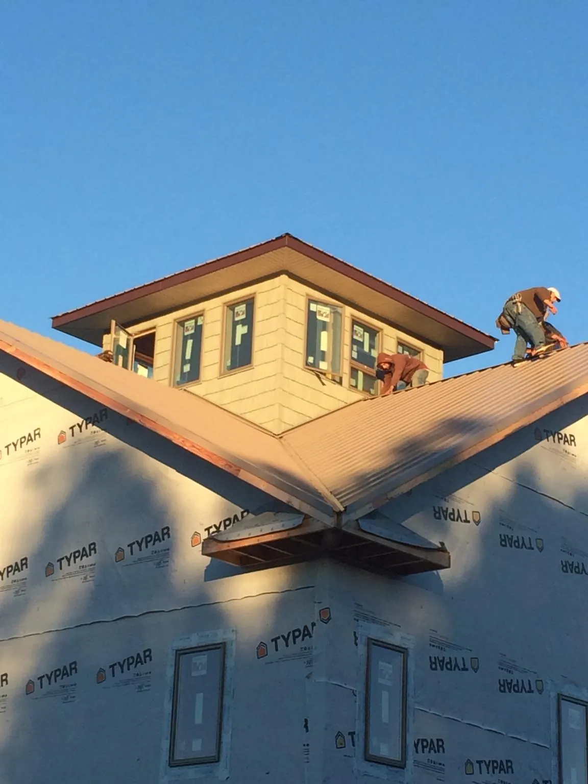 Roofers working around a rooftop cupola on a new metal roof at sunset — Roof Waterproofing in Youngtown by Roofing Brothers